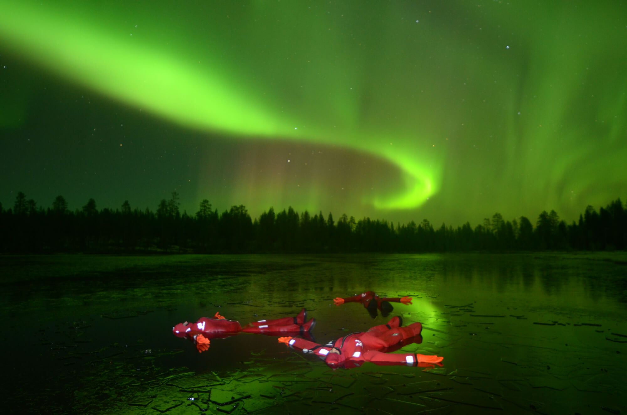 People in arctic costumes floating and watching the nothern lights.