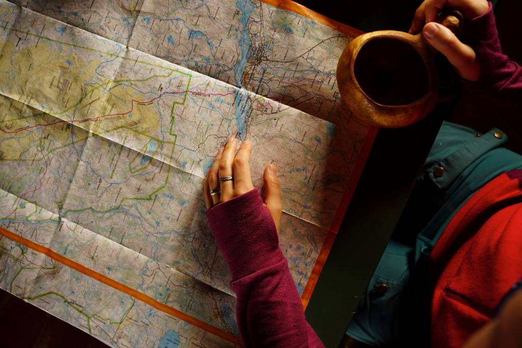 Person holding a kuksa cup, exploring a paper map