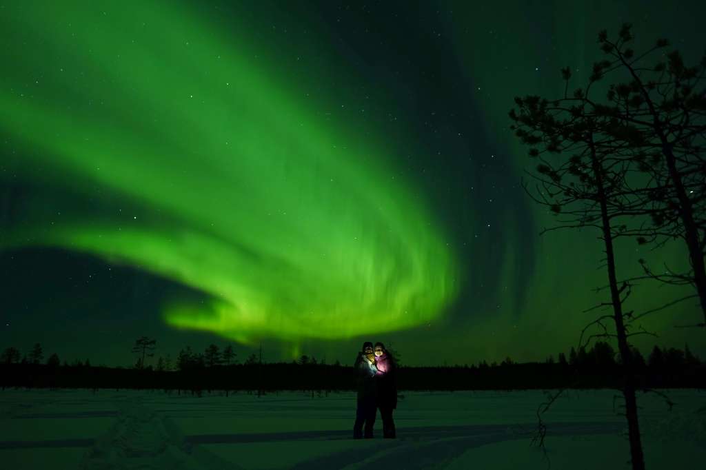 A couple standing under the Northern Lights