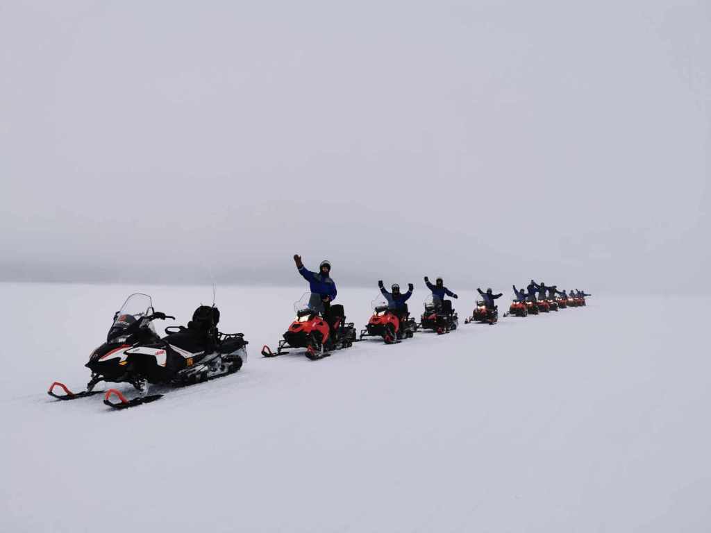 A group of tourists riding snowmobiles